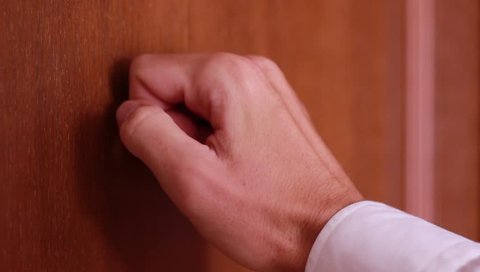 Male hand knocking on wooden door