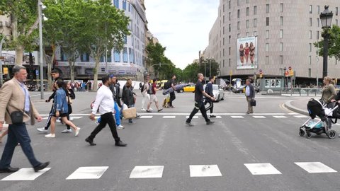 Barcelona, Spain - May 14, 2018: People crossing a road next to La Rambla famous street , downtown Barcelona.
