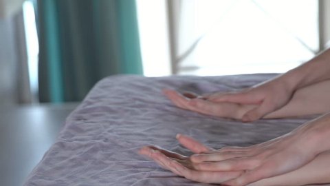 Male and female hands on the bed during sex.