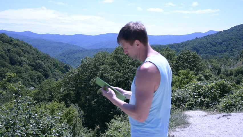 Freedom and mountains. Adult man with a tablet.
