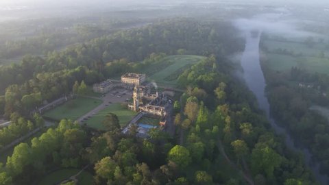 Aerial view / Drone Shot of Cliveden House in a wide frame, early morning, first light, whole estate with gardens, woodland and river within the shot and morning dew / fog in the shot, very English. 