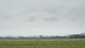 Road in flat landscape with passing cars, side view. Static daily shots