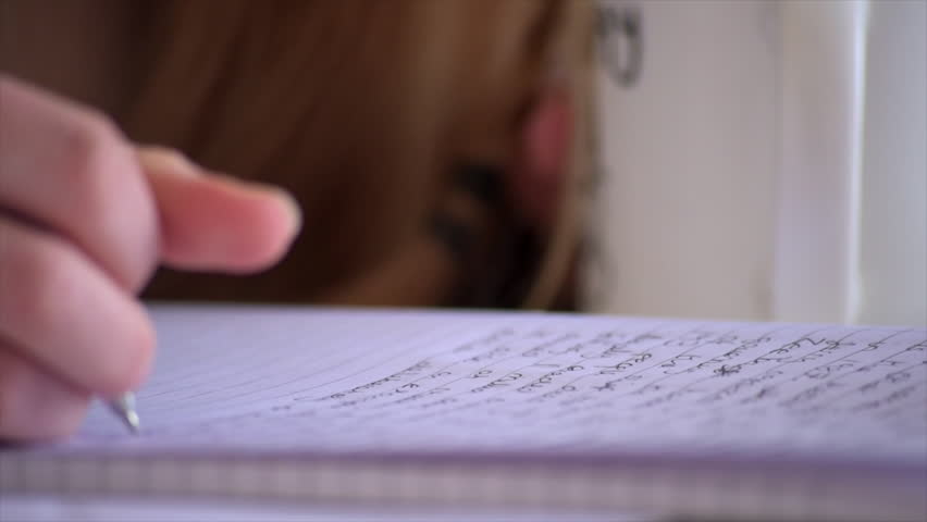 A low angle close up pull focus shot of a student making notes to study. Royalty-Free Stock Footage #1011726518