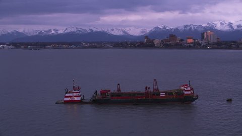 Anchorage, Alaska circa-2018. Aerial view of barge and tug boat in Anchorage, Alaska. Shot from helicopter with Cineflex gimbal and RED Epic-W camera.