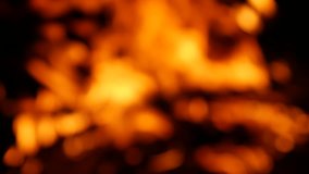 Blurry bright sparking bokeh video of a burning campfire at night in 4K resolution.