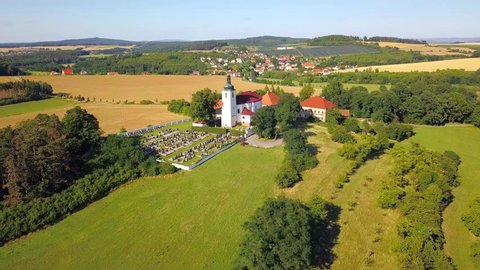 Aerial view of settlement with church, cemetery, clergy house and school on the hill in Prusiny, Nebilovy, Czech republic, European union. Beautiful scenery in rural countryside.