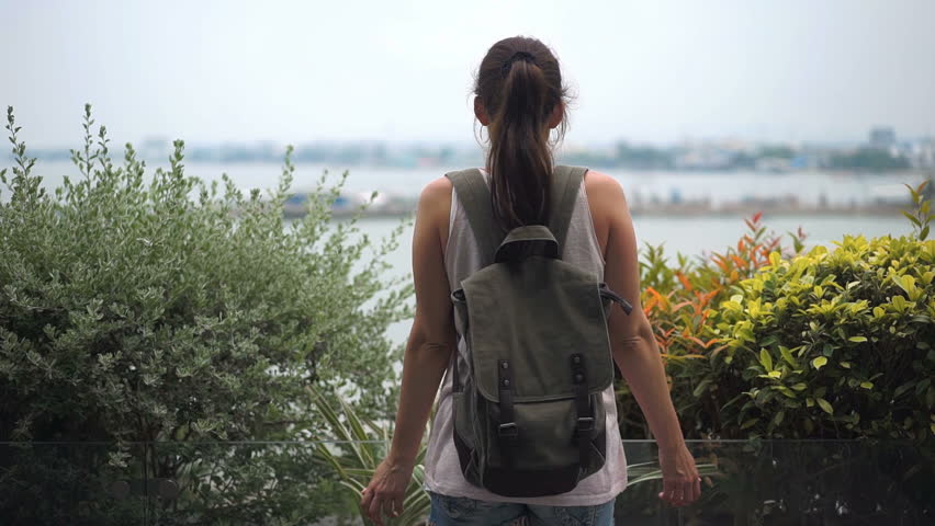 Young woman with backpack enjoying view of the landscape from the hotel. Travel concept. Back view
