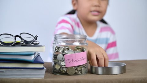 asian cute student put money to glass jar, saving money for education