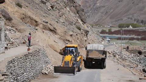 LEH LADAKH, INDIA - MAY 22, 2018: Excavator cleaning road after landslide, Unidentified road workers are removing after-effects of landslide, Ladakh, Jammu and Kashmir, India