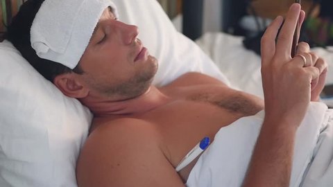 A businessman lies in a hospital with a temperature and works through a mobile phone. slow motion, 1920x1080, full hd