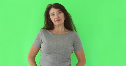 Serious wise woman looking at camera on green chromakey backdrop. Close view of somber elderly woman isolated on green screen