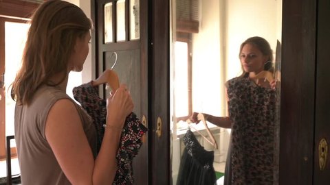 Pretty, youngl woman checking new dress in front of the mirror.
