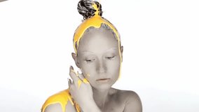 Fashion model posing on a white background with paint on his head.