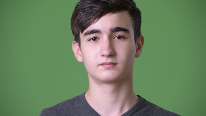 Young handsome Iranian teenage boy against green background