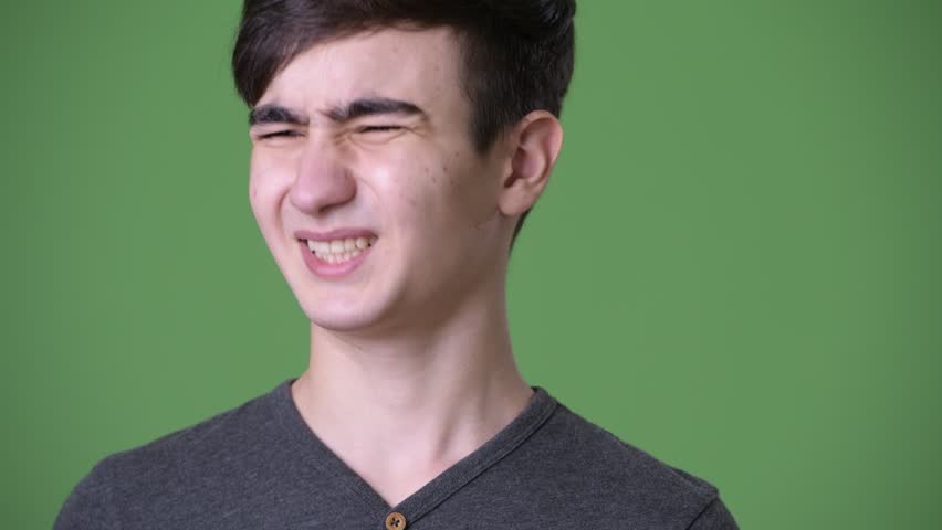 Young handsome Iranian teenage boy against green background