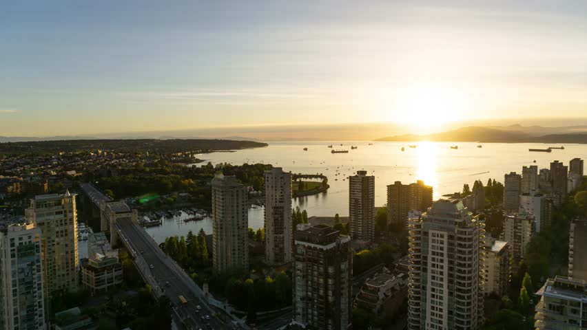 Beautiful aerial Time Lapse of a vibrant cloudy sunset above the modern city overlooking the ocean. Taken in Downtown Vancouver, British Columbia, Canada.