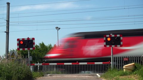 Cambridgeshire, UK - May 23, 2018: A Virgin Trains High Speed Train HST 125  passenger train heading south and a class 91 electric passenger train heading north pass over a roadway level crossing.