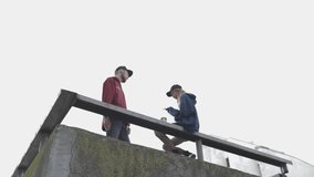 Bottom view of two people talking to each other. Beautiful young couple of man and woman standing on the edge of the building roof. City urban style. Slow motion video shooting by handheld gimbal