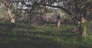 Beauty young woman enjoying nature in spring apple orchard, Happy Beautiful girl in Garden with blooming trees. 4K video shooting by handheld gimbal