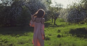 Beauty young woman enjoying nature in spring apple orchard, Happy Beautiful girl in Garden with blooming trees. 4K video shooting by handheld gimbal