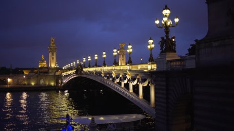 Beautiful view of night lights on Alexandre III bridge across the River Seine in Paris. In focus background of historic French landmark over body of water