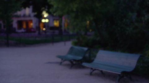 Twilight scene of park benches on dirt path in an urban setting. Night shot of out of focus benches at park in Paris