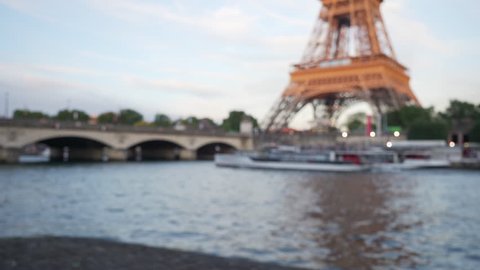 French tour boat cruising past the Eiffel Tower on the River Seine. Out of focus background plate of famous monument next to body of water in Paris France