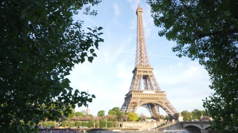 Full view of the Eiffel Tower across the River Seine in Paris. Historic French monument between two tall trees