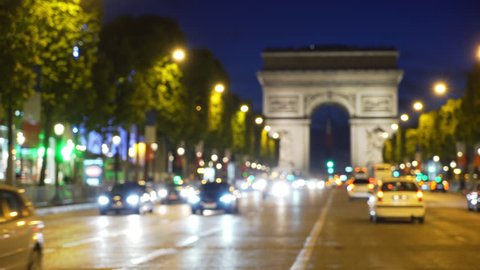 Street traffic on Champs-Elysees in front of the Arc de Triomphe in Paris France. Famous French landmark on busy avenue at night