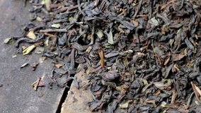 Rotating loose black darjeeling tea leaves on wooden board