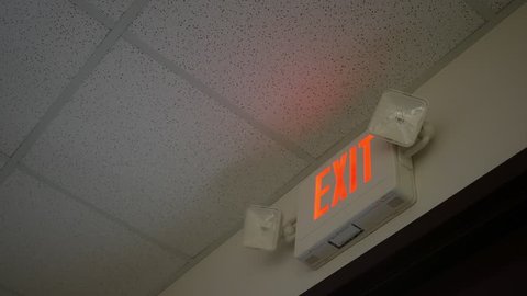 Woman testing an exit sign alarm in an office