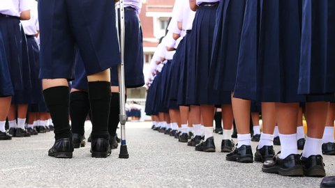 Male high school student who had bone cancer use knee prosthesis and staff for standing in line to show respect for his national anthem, Thailand, southeast Asia.