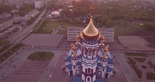 Aerial flying around new Church in small town. Christian temple and golden church dome at dawn. 4K