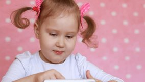 Child girl playing with a mobile phone. Baby uses a game application on the smartphone. Potrait closeup