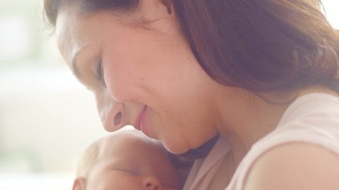 Mother and her Newborn Baby. Happy Mother holding her New born Baby girl kissing and hugging. Maternity concept. Parenthood. Motherhood. Beautiful Happy Family. Adoption. Slow motion 4K UHD 3840X2160