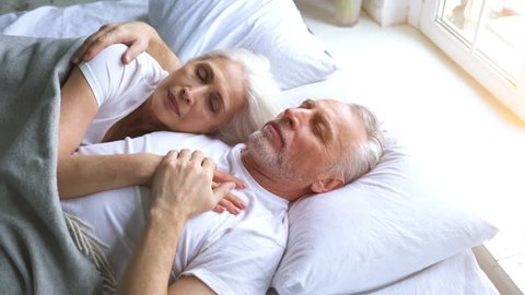 The happy elderly man and a woman laying on the bed