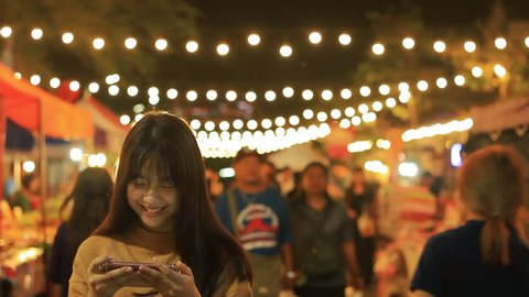 Bangkok,Thailand - June 2,2018 : asian girl play game on smartphone smiling and texting on mobile phone at Market in Bangkok, Thailand