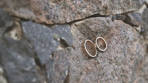 Two gold rings lie on a stone wall. Wedding in the castle. Wedding rings close-up. The stone wall holds the wedding jewelry.