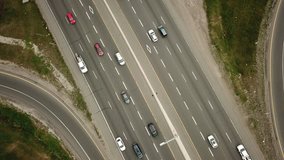 Top view aerial drone video of a massive eight lane highway.  Drone flies forwards while traffic moves underneath.