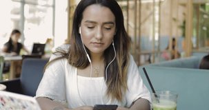 Portrait of a beautiful young woman watching a video or listening to music on mobile phone