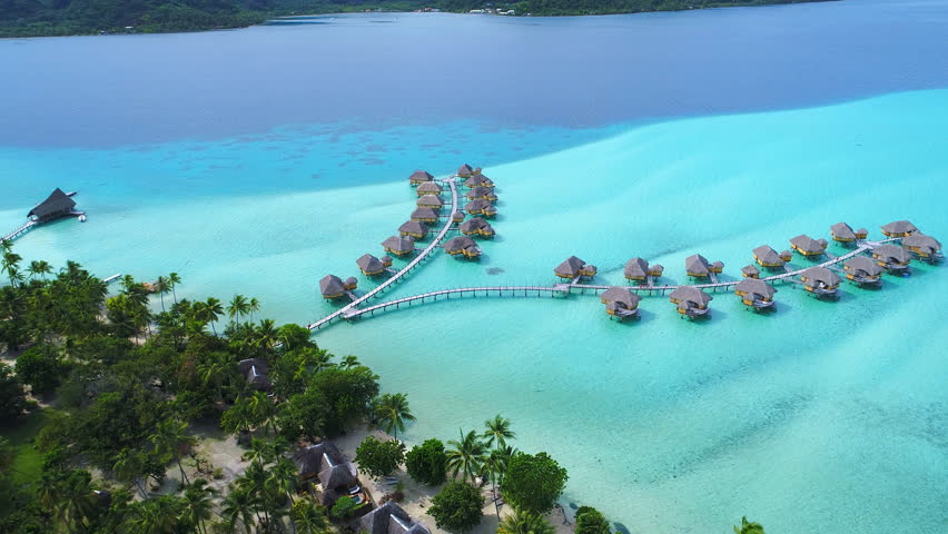 Aerial view of Motu Tautau, palm trees on little islets and turquoise water of blue lagoon, over water bungalows, tropical paradise of South Pacific Ocean - Tahaa island, seascape of French Polynesia