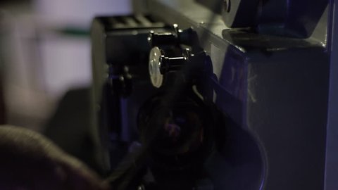 The mechanic charges the film in an old film projector. Close-up of a reel with a film