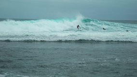 Panning clip of surfer riding a waves blue ocean. Uluwatu Beach, Bali, Indonesia - January 2018
