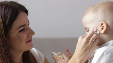 Mom wipes and cleans dirty son's face after painting. Mother care and sensitive