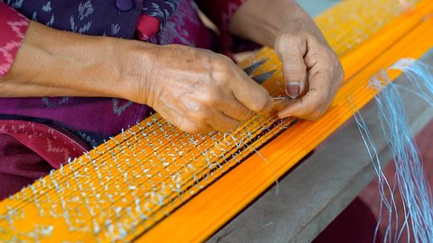 Thai Woman Making Ties Mudmee Board Weaving or Ikat Thai Silk Pattern Weaving on Small Red Weaving Mill Before Bring to Tie and Dyed in Thailand
