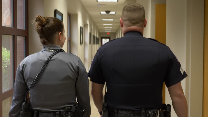 Two police officers walk down the hallway of a police department building. Royalty-Free Stock Footage #1011852824