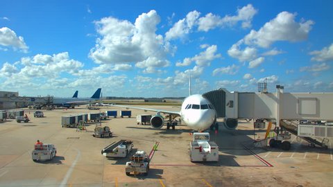 Generic Airport Concourse Exterior with Parked Airliners with Ground Support Vehicles Driving Around on a Sunny Day with White Clouds in a Blue Sky