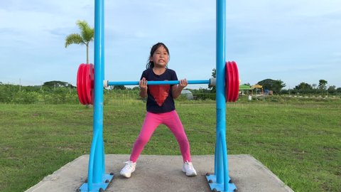 Asian kid exercise with Weight-lifting at outdoor fitness in public park, healthy concept and slow motion
