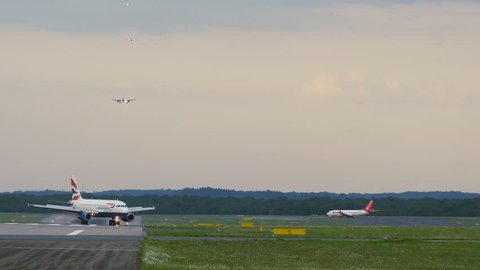 DUSSELDORF, GERMANY - JULY 22, 2017: Airbus A320 of British Airways taxiing from runway after arrived. Queue of four approaching airplanes at the background