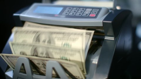 Modern currency counting machine counting dollar bills. Money counting equipment. Paper money calculation. Automatic mechanism for bank financial operations. Global economics